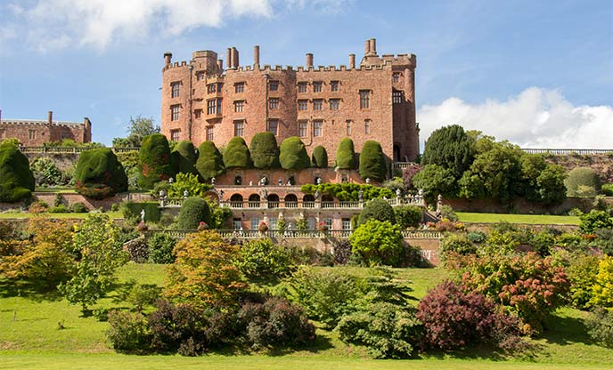 Red brick castle surrounded by lush greenery