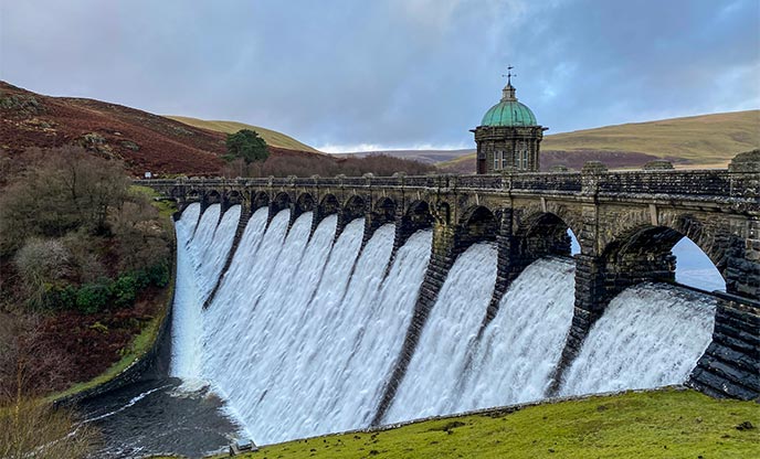 Flowing dam at Elan Valley with mountains in the background
