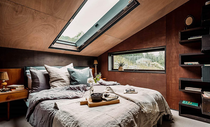 The skylight above the bed at The Lean To in Powys. The bed is made and has a tray of food and flowers sitting on it.