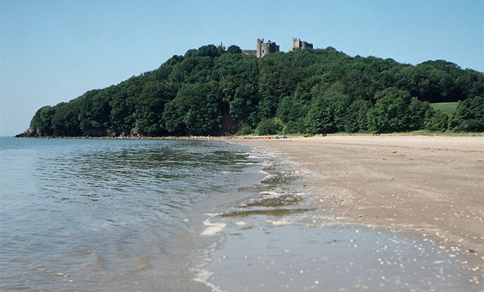 View across sandy beach up towards Llansteffan Castle