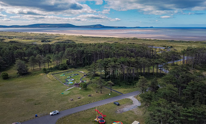 Arial view of country park with woodland and beach activities in Carmarthenshire