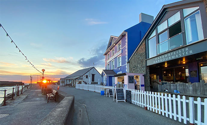 Sunset casting over the a harbour and cobalt blue pub in Wales 