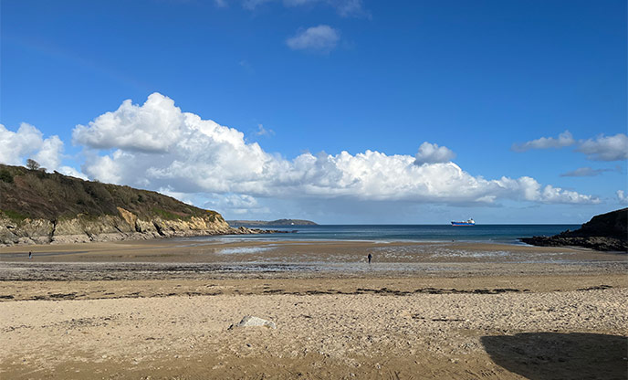 Wide stretch of sand and flat waters at Maenporth Beach