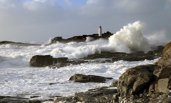Waves crashing around Godrevy Lighthouse during a storm