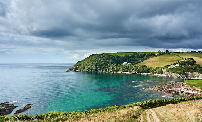 The lush green coastal walk surrounding the crystal clear waters of Talland Bay
