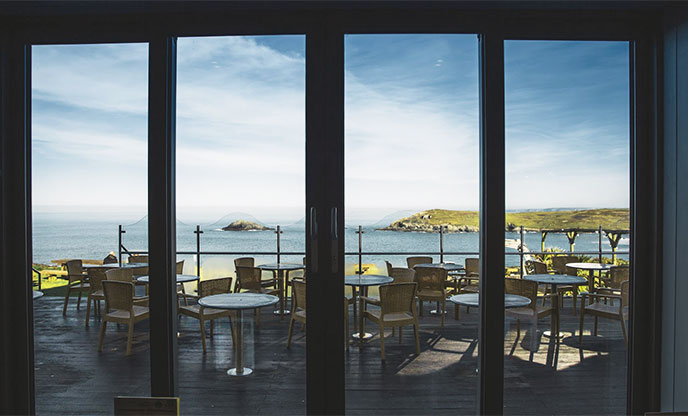 Looking out the windows across the terrace at the sea and cliffs around the Bowgie Inn in Cornwall
