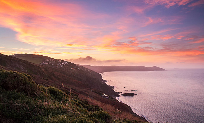 Pastel hues fill the sky as the sunrises over Rame Head at Whitsand Bay