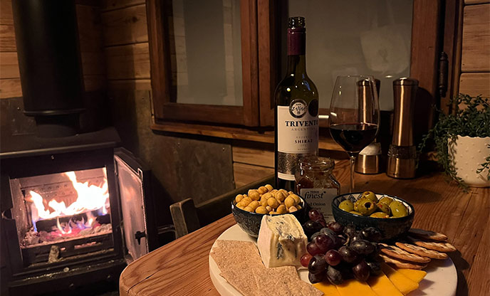 Cheese board with wine and a wood-burner roaring in the background