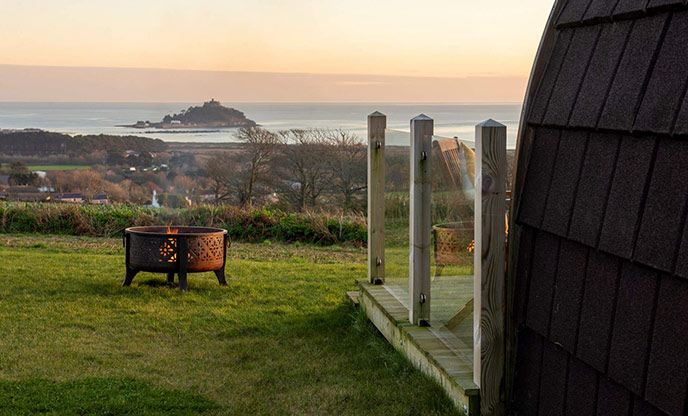 Looking past the lovely glamping pod at Scenic Bay at the firepit, which looks out over Mount's Bay towards St Michael's Mount