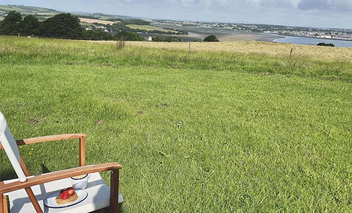 A lawn chair with pancakes and coffee looking out across the view from Tamar Hut
