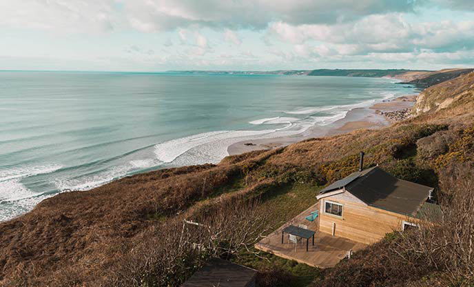 An aerial view of The Eagle, a cabin in Cornwall. It sits on the top of the cliffs, with a stunning view out to sea.