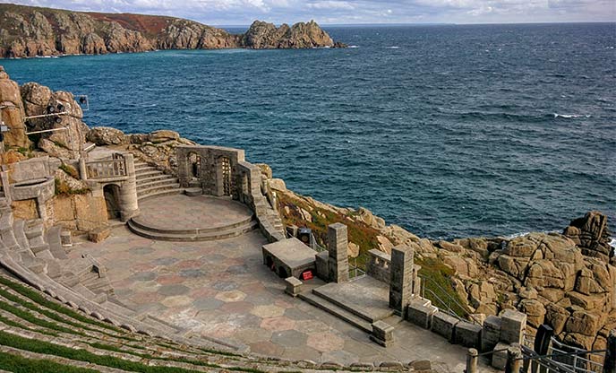 Looking down the tiered seating at the historic Minack Theatre stage with Porthcurno and the deep blue sea behind