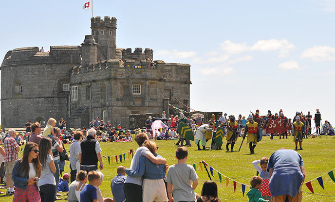 Excited crowds gather around Pendennis Castle to watch a performance of jousting