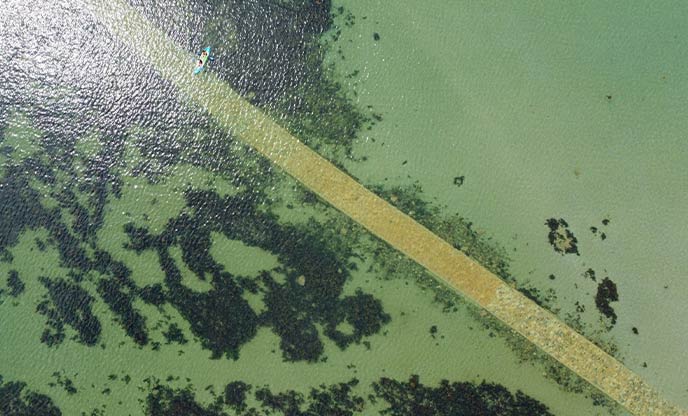 A bird's eye view of kayaks paddling across the causeway at St Michael's Mount in Cornwall