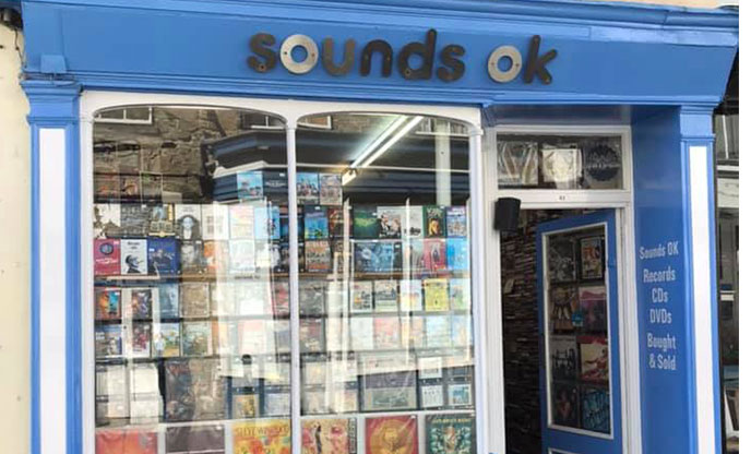 Blue exterior displaying an array of records through the shop window on record store in Falmouth