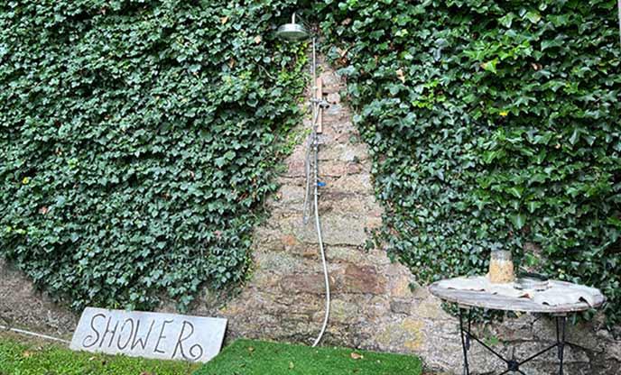 Outdoor shower against a wall of ivy