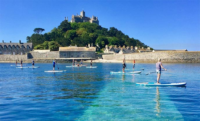 Paddle boarding over crystal clear waters in front on St Michaels Mount