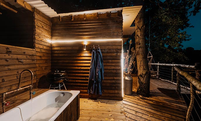 Outdoor bathtub at treehouse in Cumbria illuminated by lights