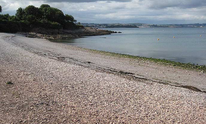 A shingle beach which slopes down to flat calm water