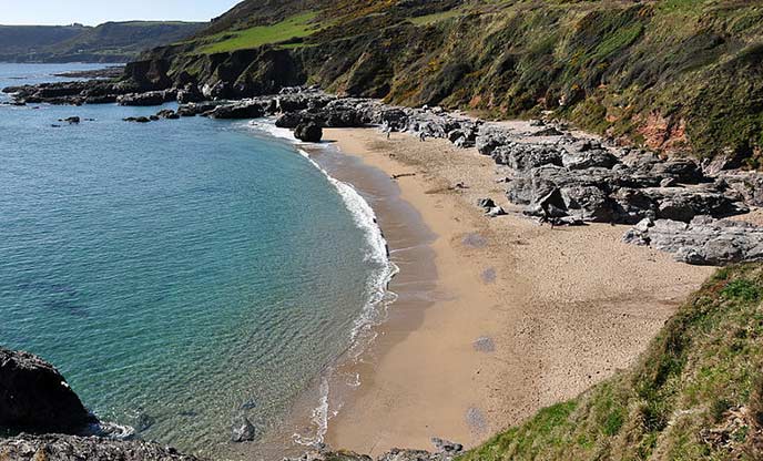 An aerial view of Mattiscombe Beach, a sandy cove with rocky edges and calm, blue sea