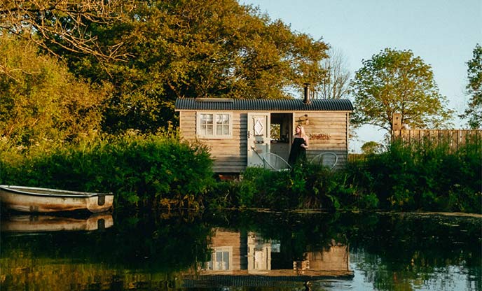 Woman outside shepherd's hut with its own private lake in Devon