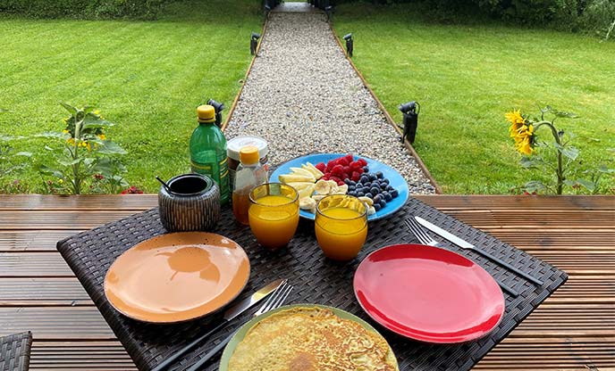 Pancakes and fresh fruit breakfast on decking