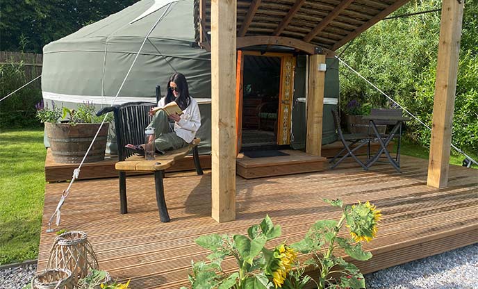 Reading on decking in front of Whittlers Yurt