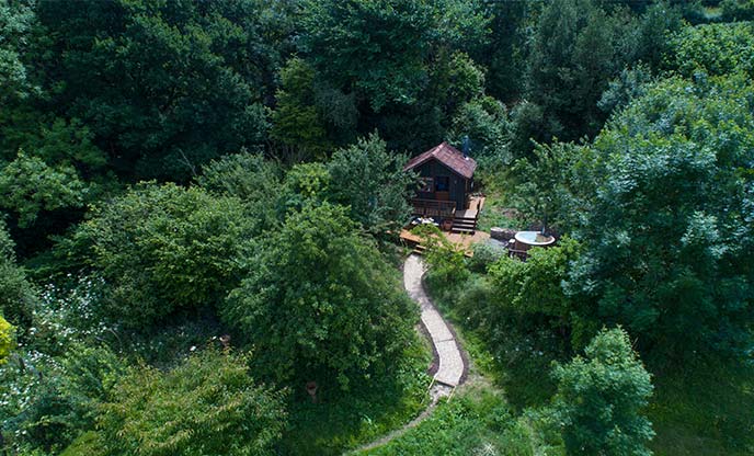 Ariel view of rustic wooden cabin in the forest with a hot tub