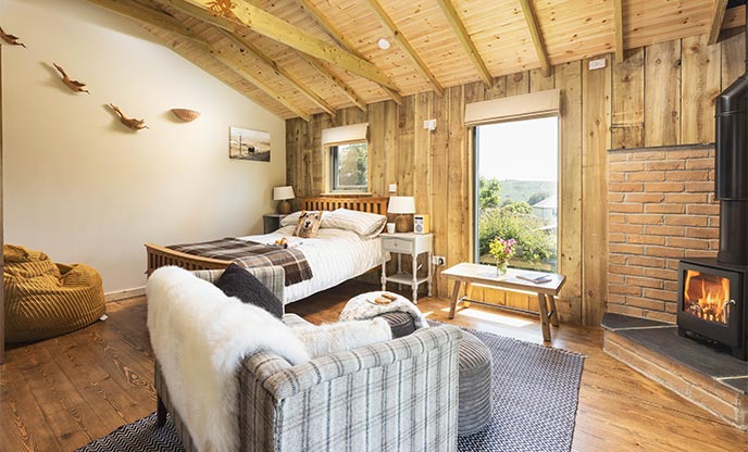 Inside cosy wooden cabin in Dartmoor with a warming wood-burner and comfy double bed