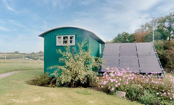 Solar panels outside of green shepherd's hut in Devon 