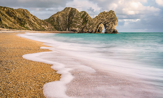 A turqoise sea lapping the shore of Durdle Door beach in Dorset