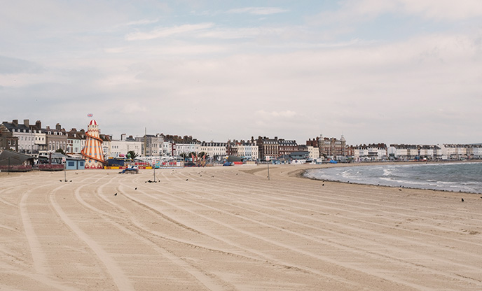 The sweeping sands of Weymouth Beach overlooked by multi-coloured townhouses