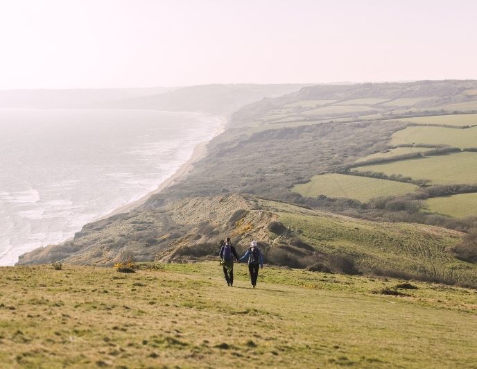 Rosita and Tom walk hand-in-hand along the incredible coastline in Dorset while staying at La Cabine Francaise