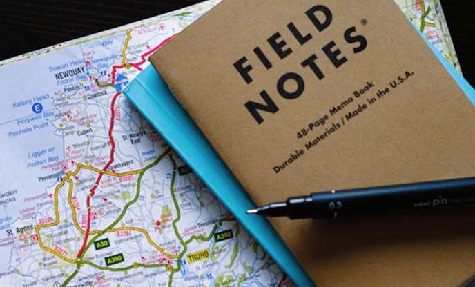 A field notes notebook sitting on top of a map of Cornwall