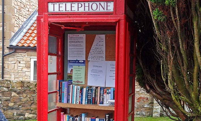 Red phonebox filled with an array of books by Wfmillar