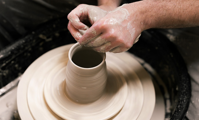 Hands working clay on a spinning pottery wheel