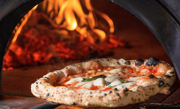 Pizza cooking in a woodfired pizza oven