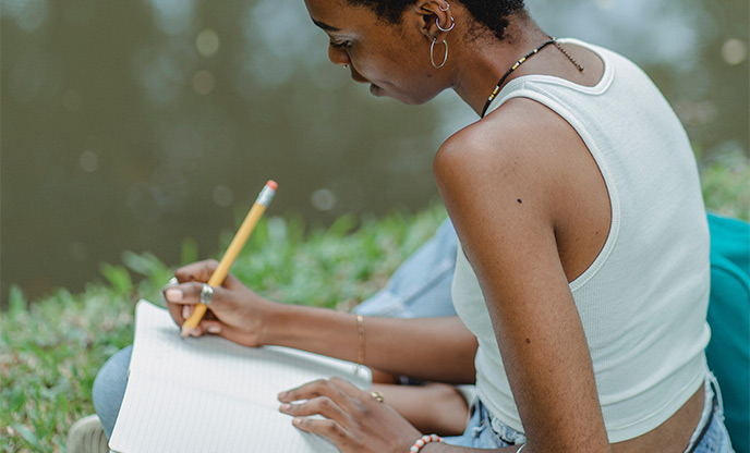Woman writing beside lake in nature