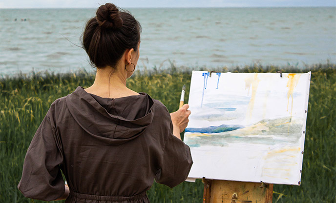 Woman painting beside the coast