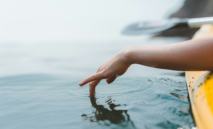 A hand dipping into the sea from a kayak