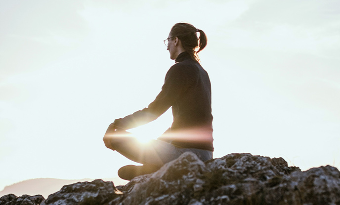 A person sitting outdoors doing yoga