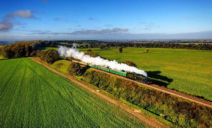 The Watercress Line steam train going through the vibrant green Hampshire countryside