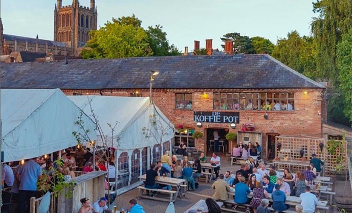 Exterior of brick cafe/bar along the bank of the River Wye with the Hereford Cathedral in the background