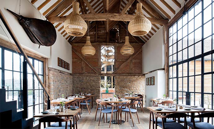 High, vaulted ceilings and large windows create a bright and airy dining room at Pensons in Herefordshire