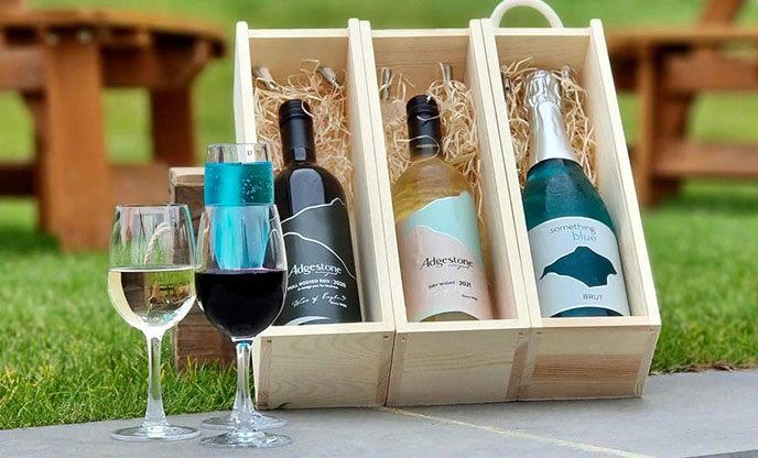 Three bottles of wine and two wine glasses on display at Adgestone Vineyard