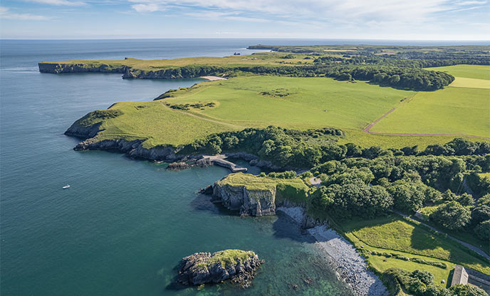 Arial view of the rugged coast and flat ocean at Stackpole