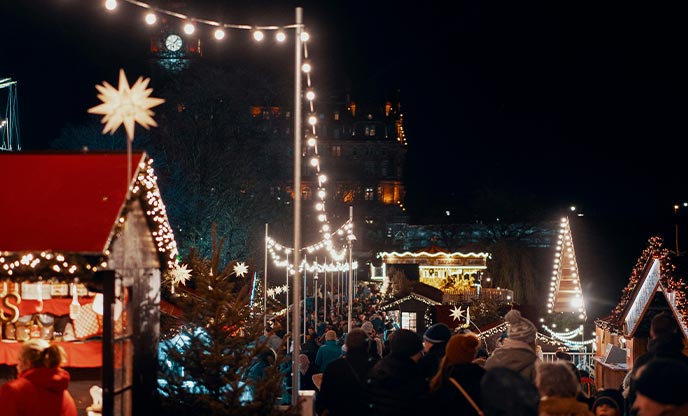 Outdoor Christmas market stalls lit up by fairy lights