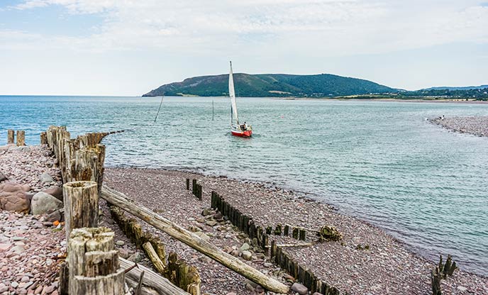 A little red boat sails along the sea front at Porlock Weir, one of the lovely beaches in Somerset