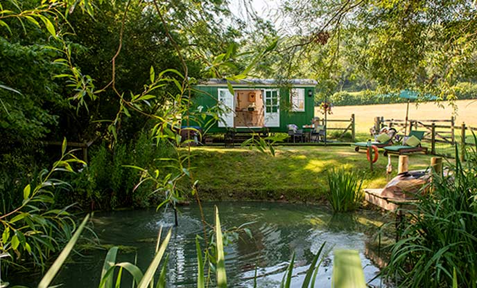 Green shepherd's hut nested amongst nature with a lake 