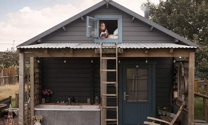 Abbie looking out of a small bedroom window reading a book